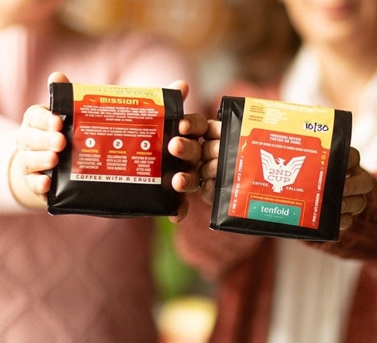 Hands holding bags of A 2nd Cup coffee beans